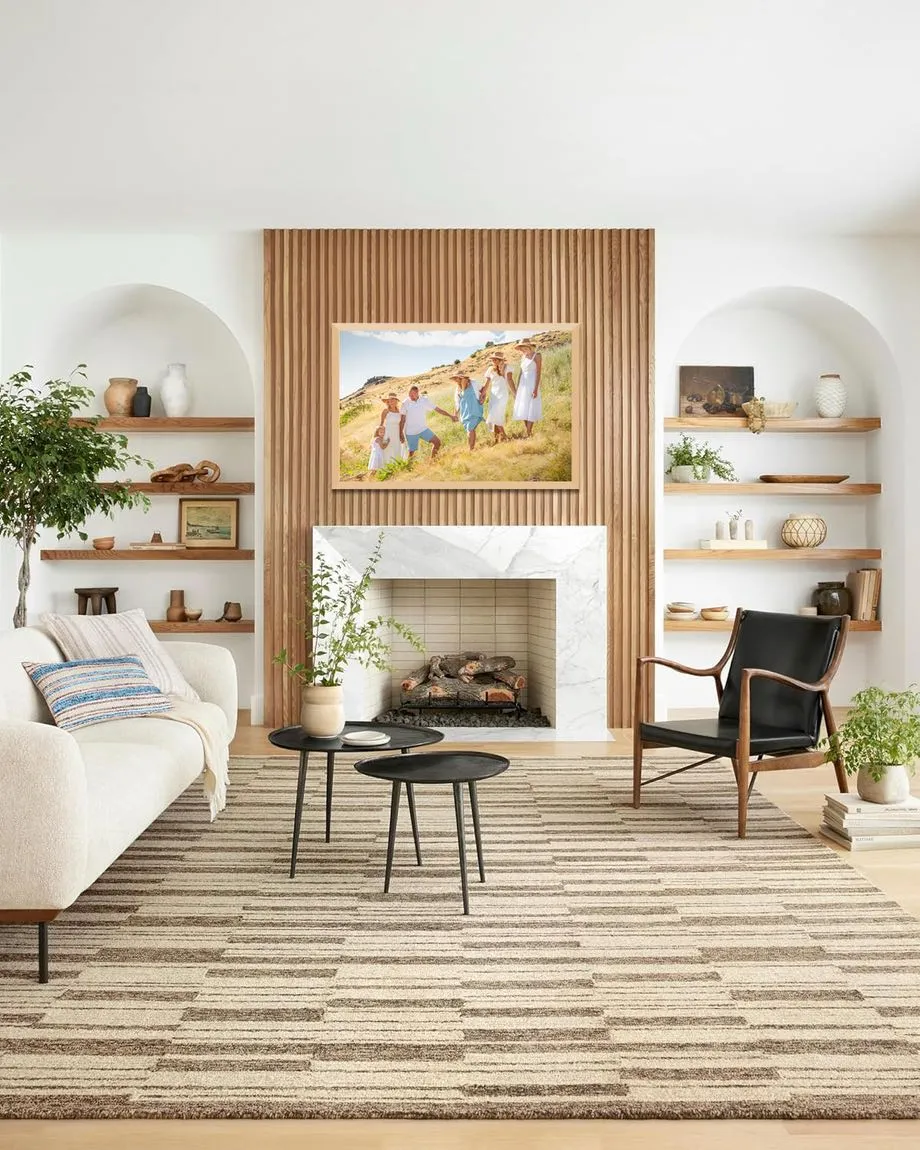 A framed family portrait above a fireplace in a light, modern living room